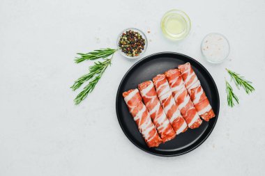 Domuz pastırması siyah tabakta baharat ve biberiye ile sarılmış.