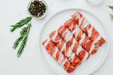 Jambona sarılmış sosis, beyaz tabakta otlar ve yağla birlikte.