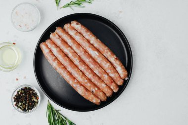 Siyah tabakta taze domuz sosisi, biberiye ve tuz.