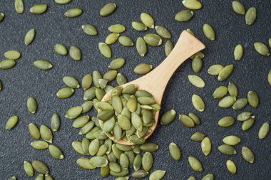 Tahta kaşıkta kabak çekirdeği ve etrafa yayılmış tohumlar.