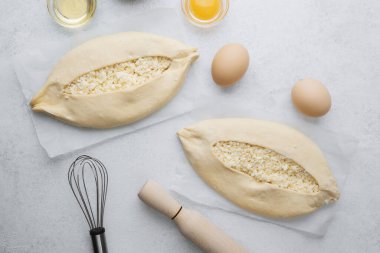Işık yüzeyinde peynirli ve yumurtalı iki çiğ khachapuri.