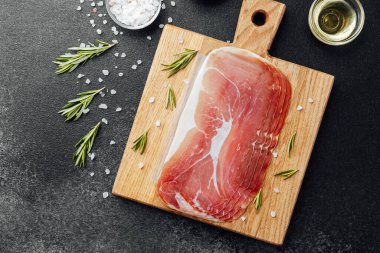 Tahtada deniz tuzu ve biberiyeyle jambon dilimleri var.