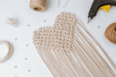 Beyaz arka planda tutkal tabancası ve kablosu olan kalp makromu.