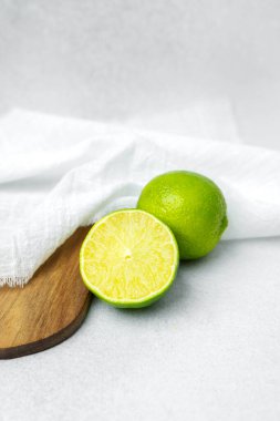 Parlak limonlar beyaz bir kumaşın yanında tahta bir kesme tahtasına dizilmiş..