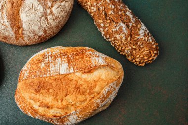 Çeşitli doku ve şekillere sahip zanaatkar ekmekler koyu bir arkaplanda düzenlenmiştir..