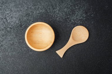 Yemek hazırlamak ve servis etmek için yapılmış eşleşen bir kaşığın yanında ahşap bir kase..