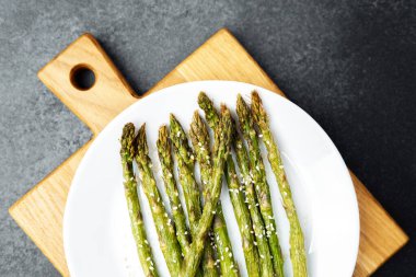 Taze ızgara kuşkonmaz beyaz bir tabakta susam tohumlarıyla süslenir..