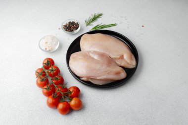 Çiğ tavuk göğsü ve taze domates, tuz, biber ve biberiye.