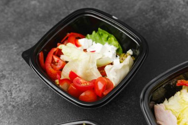 Yemek hazırlama ya da sağlıklı yemek hazırlama konsepti için içinde gurme malzemelerinin bulunduğu siyah kaplarda çeşitli taze salatalar.