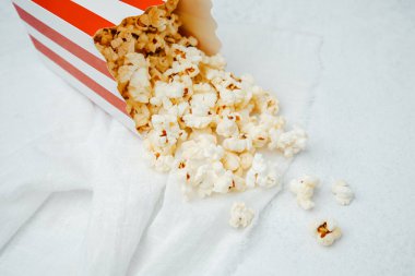 Patlamış mısır kırmızı beyaz bir torbadan yumuşak beyaz bir yüzeye dökülüyor..