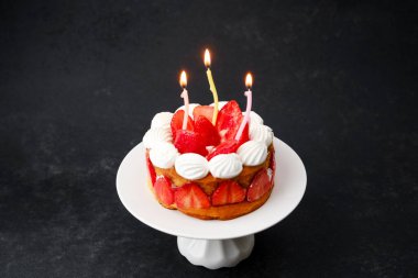 Mumlu doğum günü çilekli pasta. Karanlık arka planda festival partisi için tatlı konsepti.