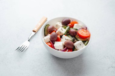 Beyaz kasede salatalık ve domatesli peynirli Yunan salatası.