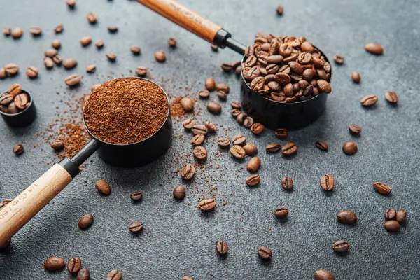 Ground Coffee ve gri arka planda kepçeli fasulyeler.