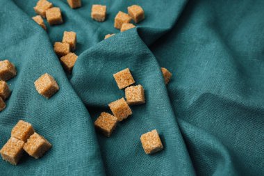 Küçük kahverengi şeker küpleri desenli bir mavi kumaş yüzeyinde dinleniyor..