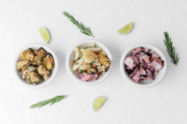 En az besin bileşimi ya da diyet konsepti için beyaz zemin üzerinde otlu ve limonlu üç deniz ürünleri kasesi.