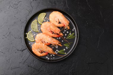 Limonlu büyük karides tabağı. Lüks deniz ürünleri veya yemek konsepti için koyu arka planda.