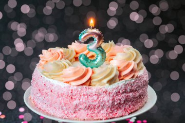 Güzel dekore edilmiş bir pasta pembe krema ve üç numaralı mumu içerir..