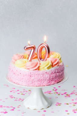 Kutlama atmosferinde mumlarla kaplı canlı pembe bir doğum günü pastası..