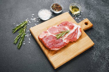 Biberiyeli çiğ biftek ve ahşap tahtada baharatlar.