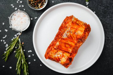 Beyaz tabakta marine edilmiş domuz pirzolası ve baharat.