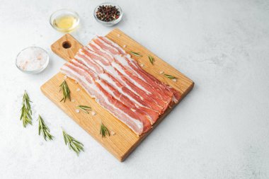 Ahşap tahtada çiğ pastırma dilimleri, biberiye ve koyu arkaplanda tuz.