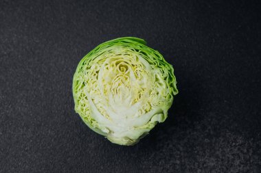 Siyah zemin üzerinde eşmerkezli yaprak katmanları olan yarım lahana.