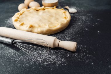 Hamur, çırpılmış çırpı ve oklavayla karanlık bir mutfak tezgahına yuvarlanır..