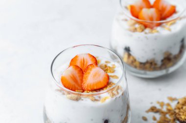Dilimlenmiş çilek ve tahıl gevreğiyle kaplı yoğurt parfe.