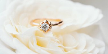 Beyaz gül arkaplanındaki nişan yüzüğü