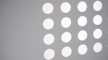 Parlak beyaz daireler pürüzsüz gri bir yüzey üzerinde temiz bir desen oluşturur. Bu soyut geometrik tasarım minimalist bir arkaplan oluşturur.