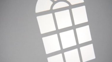 Parlak güneş ışığı düz bir duvarı aydınlatır, kemerli bir pencere çerçevesinden belirgin, soyut bir gölge deseni yaratır, arka plan olarak mükemmel..