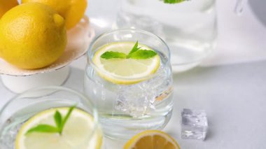 Nane şekerli ve buzlu soğuk limon suyu, parlak sarı limonlarla birlikte berrak bardaklarda sunuluyor..