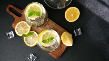 Buz küplü soğuk limon ve naneli içecekler güzel bir şekilde koyu bir yüzey ve ahşap tahta üzerinde sergilenir..