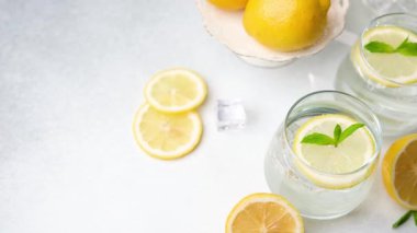 Ferahlatıcı limon suyu içecekleri, taze nane yaprakları ve buz küpleri, yaz mevsimi için ideal, hafif bir arka planda mükemmel bir şekilde düzenlenmiştir..