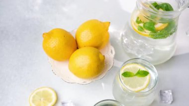 Taze limon dilimleri ve nane yapraklı soğuk su, sarı limon ve buz küpleriyle birlikte güzelce sergilenir..