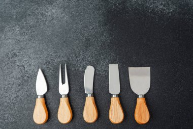 Beş paslanmaz çelik bahçe aletinin ahşap sapları düzgün yerleştirilmiş, kolay erişim için..