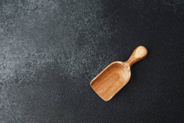 Tahta kepçe koyu dokulu bir yüzeye dayanır. Malzemeleri ölçmek için idealdir..