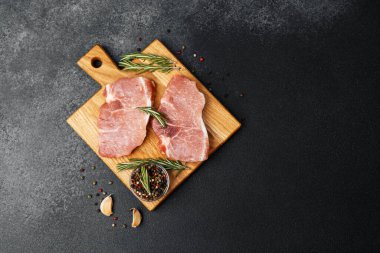 İki çiğ domuz pirzolası yakındaki bir tahtaya konur..