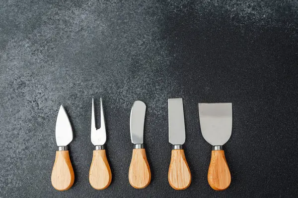 Beş paslanmaz çelik bahçe aletinin ahşap sapları düzgün yerleştirilmiş, kolay erişim için..