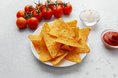 Domatesli nacho cipsi, beyaz arka planda tuz ve sos.