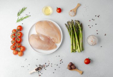 Çiğ tavuk göğsü beyaz tabakta sebzeler ve baharatlar masada!