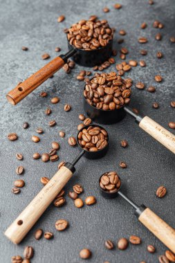 Kahve çekirdekleri gri arka plandaki kepçeleri ölçüyor