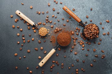 Ground Coffee ve gri arka planda kepçeli fasulyeler.
