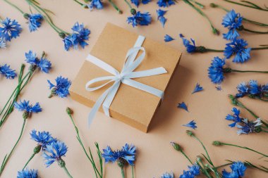 Bej arkaplanda çiçek olan hediye kutusu