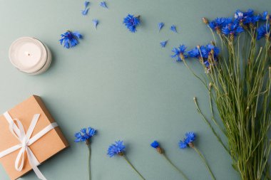 Yeşil zemin üzerinde mum, hediye kutusu ve çiçek fotokopi alanı ile