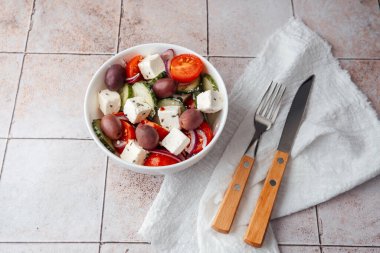 Çatal ve bıçakla fayans zemininde Yunan salatası