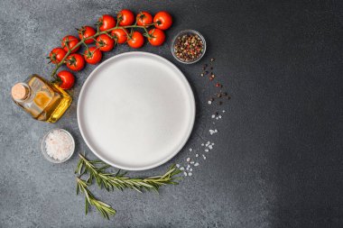 Boş beyaz tabak, zeytinyağı biberiye biber, tuz ve kiraz domatesli koyu masa.