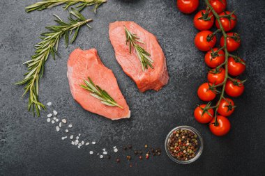 Siyah arka planda biberiyeli taze çiğ biftek ve tuz ve baharat.