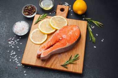 Tahtada taze somon dilimleri, limon, ot ve baharatlar..