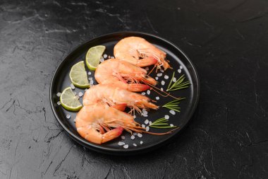 Limonlu büyük karides tabağı. Lüks deniz ürünleri veya yemek konsepti için koyu arka planda.